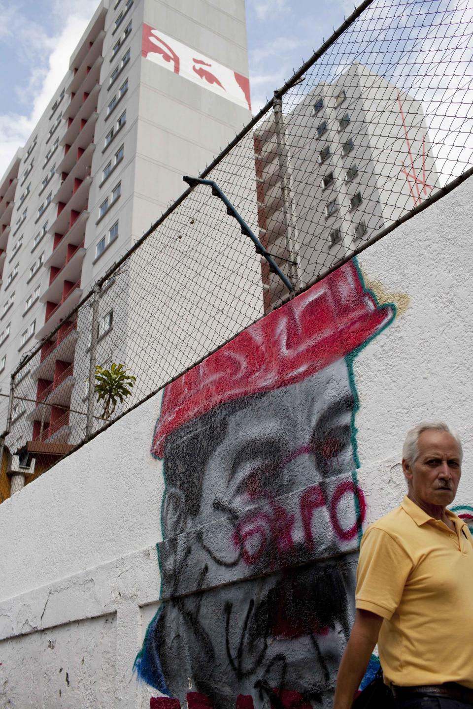 Un hombre pasa junto a un grafiti con una pintura con el rostro del presidente de Venezuela Nicolás Maduro en el centro de Caracas, Venezuela, el jueves 20 de febrero de 2014. Las protestas han recrudecido en Venezuela mientras el líderr opositor Leopoldo López enfrenta cargos criminales por los incidentes ocurridos tras una marcha en Caracas la semana pasada. (AP Photo/Rodrigo Abd)