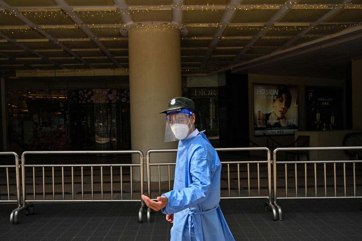 A security guard stands outside the entrance of a closed shopping mall (Hector Retamal / AFP via Getty Images)