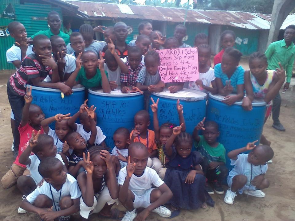 Students in Liberia with barrels of books collected by Library for Africa.