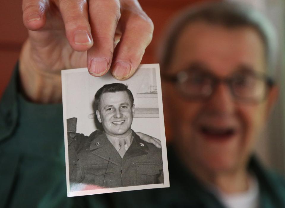 Tonie Darvid of Portsmouth is now 97 and holds up a photograph of himself when he was in the Army on July 16, 2021 at his home in Portsmouth.