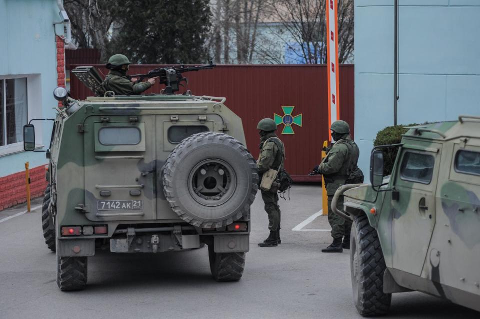 Troops in unmarked uniforms stand guard as they take control the Coast Guard offices in Balaklava on the outskirts of Sevastopol, Ukraine, Saturday, March 1, 2014. An emblem on one of the vehicles and their number plates identify them as belonging to the Russian military. Ukrainian officials have accused Russia of sending new troops into Crimea, a strategic Russia-speaking region that hosts a major Russian navy base. (AP Photo/Andrew Lubimov)