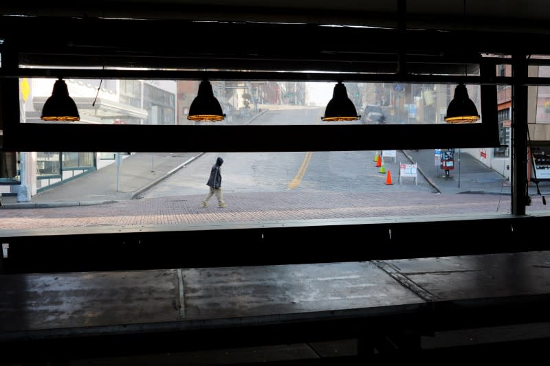 A pedestrian passes empty stalls at the Public Market, amid the coronavirus disease outbreak, in Seattle