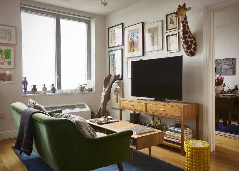 A dinosaur bone next to a large TV and a wooden media center. The white living room also features a green couch.