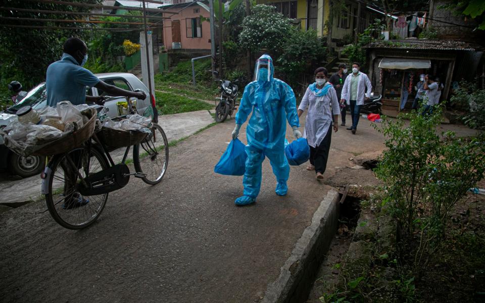 A health worker walks during a door-to-door drive to take nasal swab samples in Gauhati, India - AP