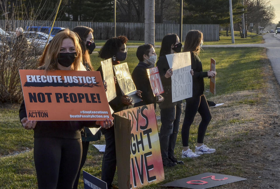 Protesters line Prairieton Road across from the Federal Execution Chamber, Thursday, Dec. 10, 2020 in Terre Haute, Ind. The execution Brandon Bernard, convicted in the 1999 killing of two youth ministers in Texas is scheduled Thursday at the federal prison in Terre Haute, Indiana.. (Austen Leake/The Tribune-Star via AP)