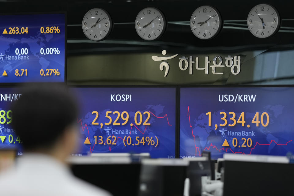 A currency trader walks by the screens showing the Korea Composite Stock Price Index (KOSPI), center, and the foreign exchange rate between U.S. dollar and South Korean won at a foreign exchange dealing room in Seoul, South Korea, Friday, May 19, 2023. (AP Photo/Lee Jin-man)