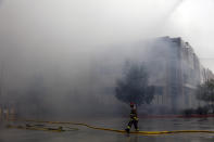 A firefighter watches as smoke from a burning warehouse fills the air Friday, June 5, 2020, in Redlands, Calif. The fire destroyed the commercial building, about 60 miles east of Los Angeles, but there are no reports of injuries. (AP Photo/Jae C. Hong)