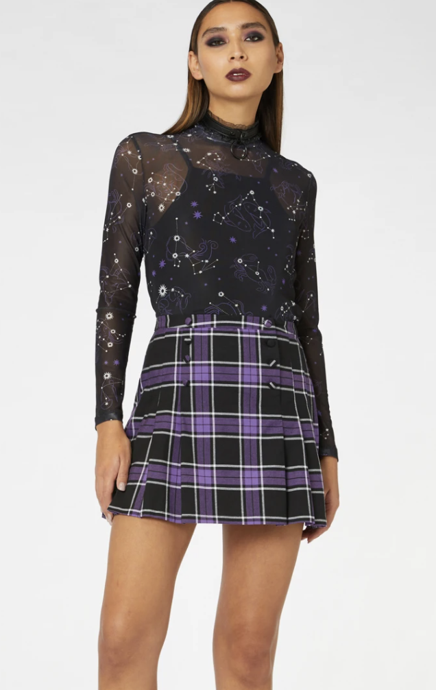 Model wears purple and black plaid mini Aura Skirt, now $37, from Dangerfield, with black sequinned transparent top over black camisole