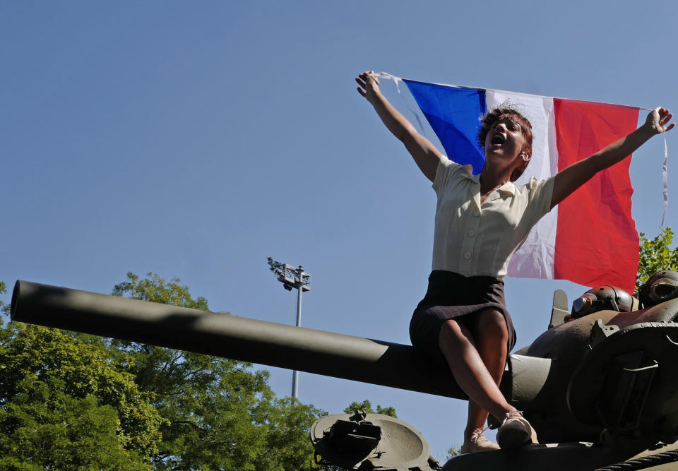 A woman waves a French flag during celebrations of the liberation of Paris from Nazi occupation exactly 75 years ago, in Paris, Sunday, Aug. 25, 2019. People dressed in World War II-era military uniforms and dresses are parading in southern Paris, retracing the entry of French and U.S. tanks into the city on Aug. 25, 1944. (AP Photo/Michel Spingler)