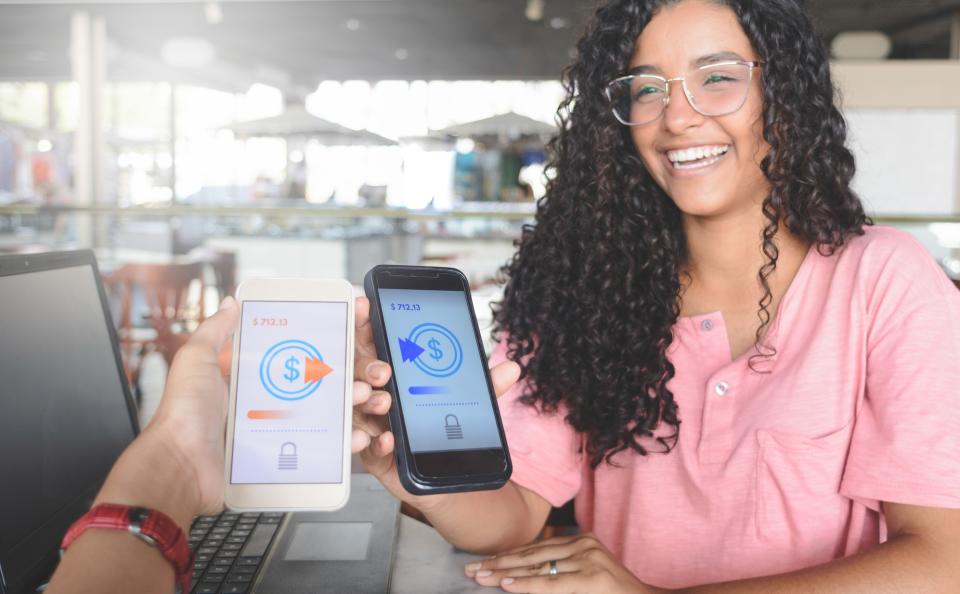 Young women sending money through digital wallet, using smartphones.