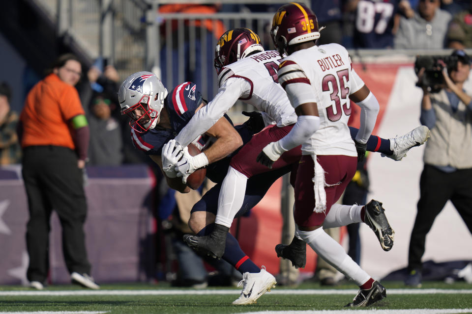 New England Patriots tight end Hunter Henry, left, pulls in a pass for a touchdown as Washington Commanders linebacker Khaleke Hudson, center, and safety Percy Butler, right, defend in the first half of an NFL football game, Sunday, Nov. 5, 2023, in Foxborough, Mass. (AP Photo/Charles Krupa)