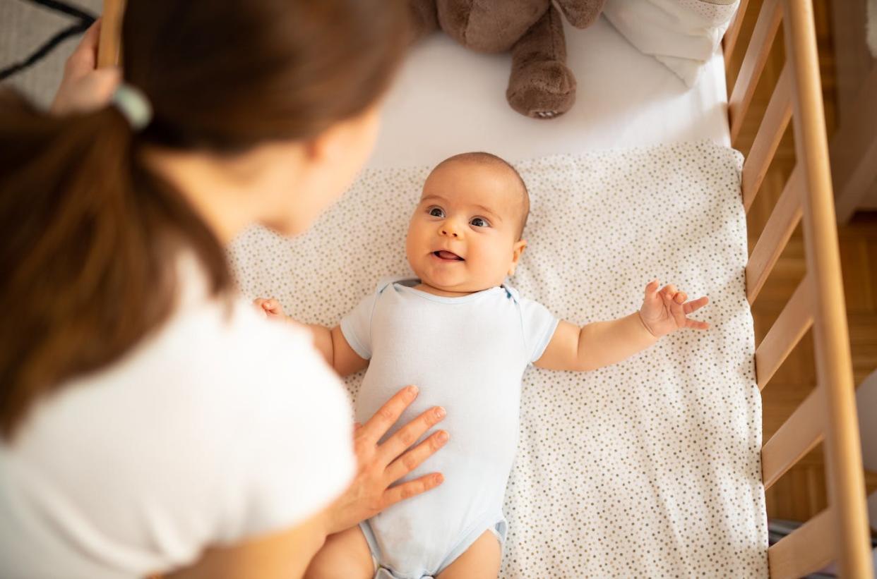 Babies should sleep on their back on a firm, flat surface. <a href="https://www.gettyimages.com/detail/photo/mother-putting-her-baby-to-sleep-woman-bending-royalty-free-image/1195477301?phrase=baby%20sleeping%20in%20crib&adppopup=true" rel="nofollow noopener" target="_blank" data-ylk="slk:mdphoto16/E+ via Getty Images;elm:context_link;itc:0;sec:content-canvas" class="link ">mdphoto16/E+ via Getty Images</a>