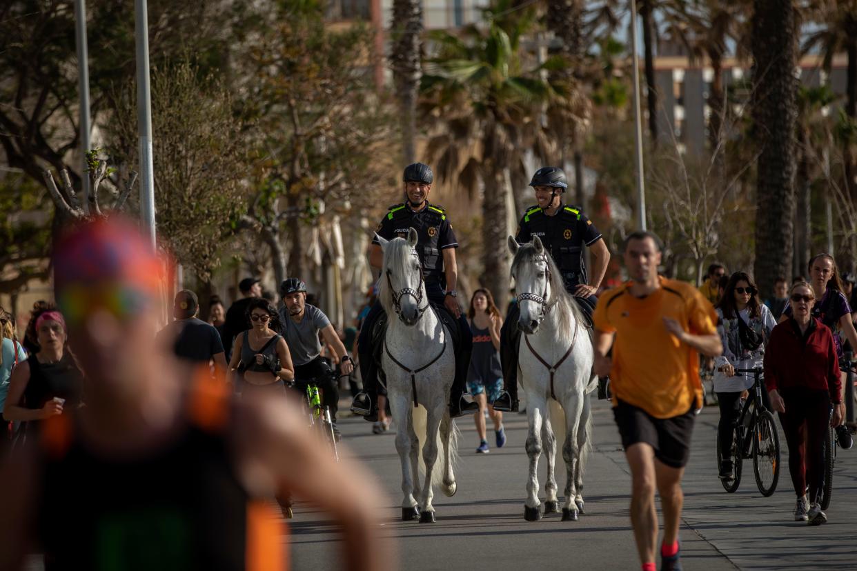 Mounted police patrol on horses as people exercise on a seafront promenade in Barcelona, Spain on Sunday, May 3, 2020. Spaniards have filled the streets of the country to do exercise after seven weeks of confinement to their homes to fight the coronavirus pandemic.