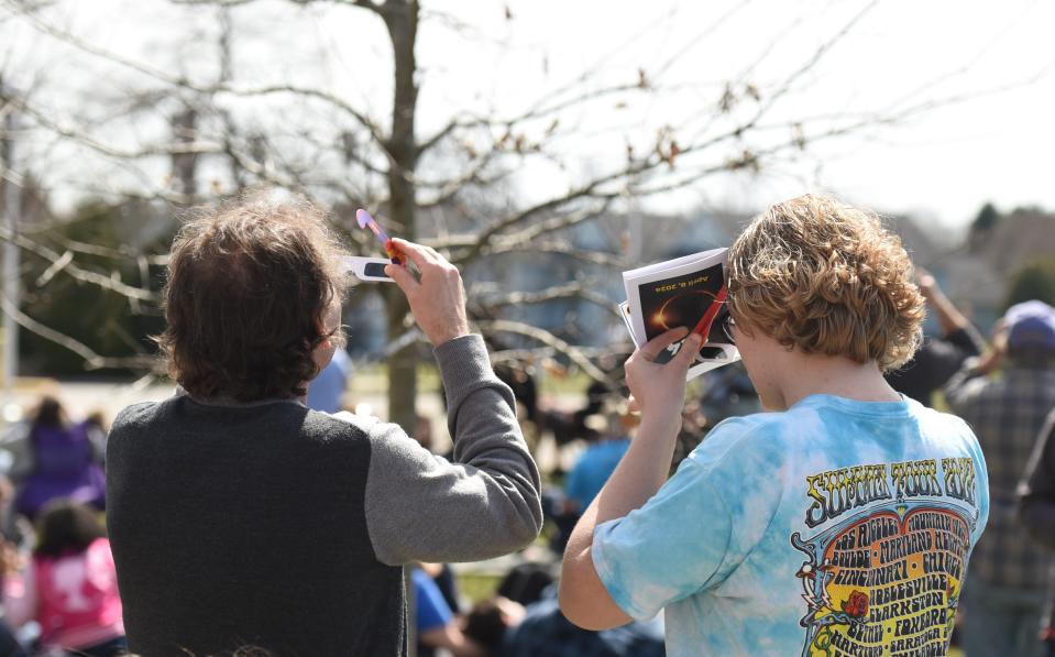 Evan Walker, right, watches the solar eclipse with his father using glasses provided by St. Clair Community College on April 8, 2024.