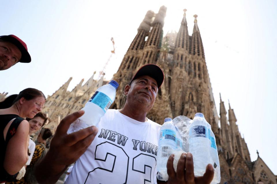 Un hombre vende botellas de agua a los turistas que esperan para entrar en la iglesia de la Sagrada Familia de Barcelona (Reuters)
