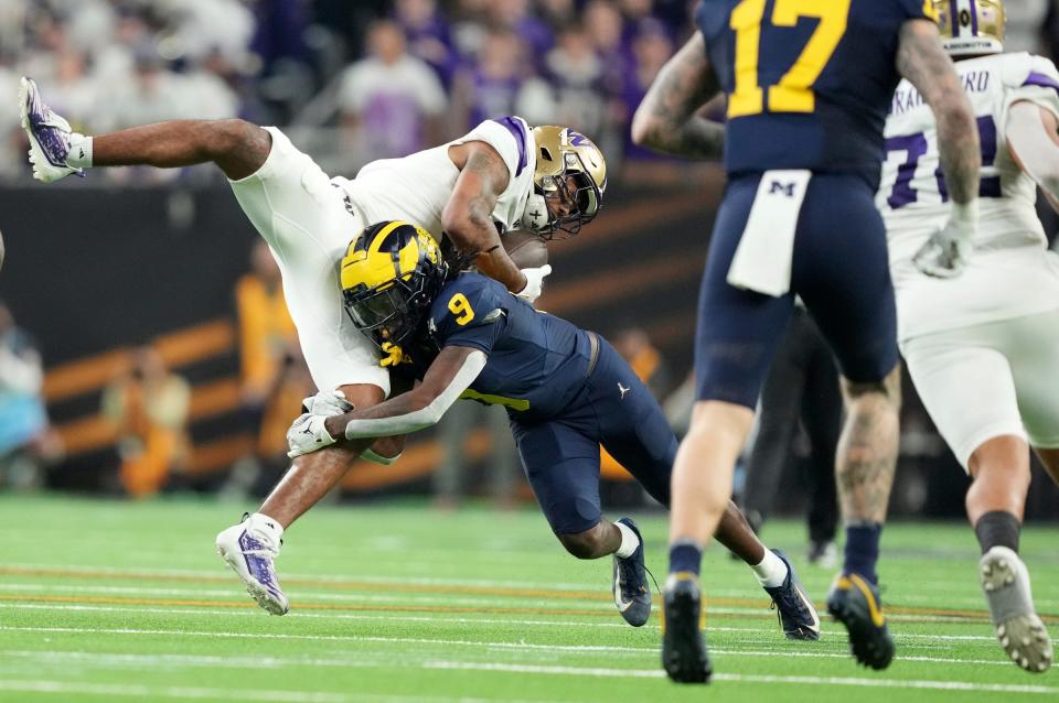 Washington wide receiver Ja'Lynn Polk is tackled by Michigan defensive back Rod Moore during the second half of the College Football Playoff national championship game against Washington at NRG Stadium in Houston, Texas on Monday, Jan. 8, 2024.