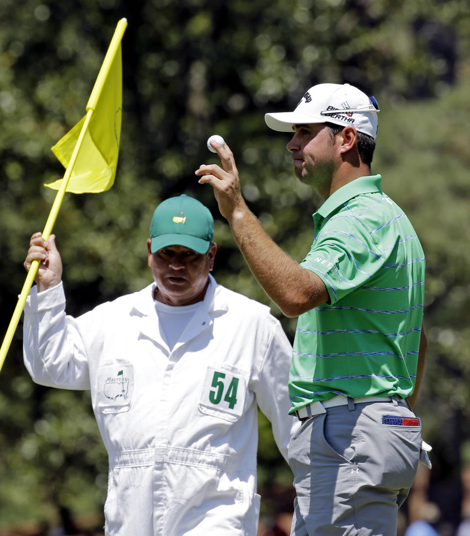 Caddie Tony Navarro looks at Gary Woodland as he holds up his ball after a birdie on the 10th hole during the third round of the Masters golf tournament Saturday, April 12, 2014, in Augusta, Ga. (AP Photo/David J. Phillip)