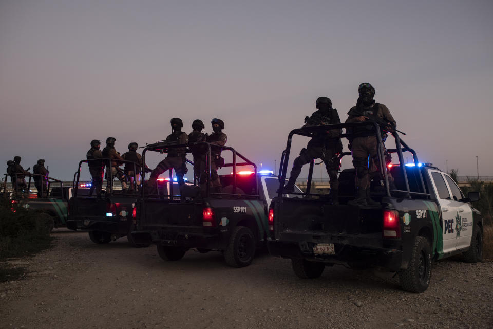 Mexican police stand guard near the Rio Grande river in Ciudad Acuna, Mexico, at dawn Thursday, Sept. 23, 2021, on the border with Del Rio, Texas. Mexico has been ramping up efforts to relieve migrant numbers at this segment of the border. (AP Photo/Felix Marquez)
