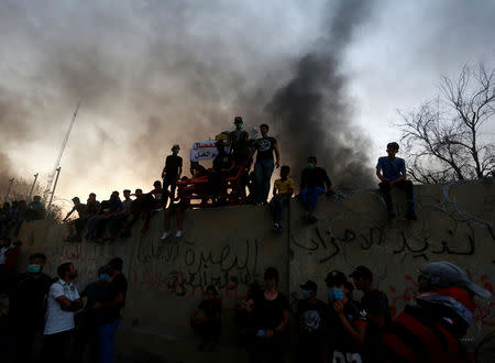 Iraqi protesters stand on concrete blast walls during an anti-government protest near the burnt building of the government office in Basra, Iraq September 7, 2018. REUTERS/Alaa al-Marjani