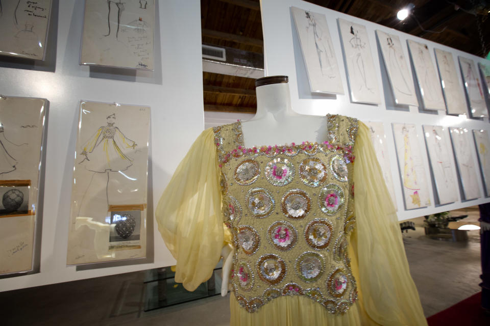 This Monday, Dec. 30, 2013, photo shows one of the dresses that Karl Lagerfeld did along with the drawings he made for the dress, in West Palm Beach, Fla. A 50-year-old archive of some of Karl Lagerfeld’s early fashion designs is going up for auction in Florida. In the 1960s, Lagerfeld was designing for Elizabeth Taylor and other celebrities while working for the House of Tiziani in Rome. (AP Photo/J Pat Carter)