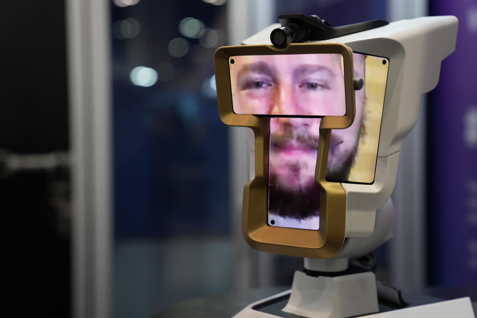 A man looks onto the show floor from a Wehead spatial video communication device at the Wehead booth during the CES tech show Friday, Jan. 6, 2023, in Las Vegas. The device, controlled via a smartphone, laptop, or tablet, allows the user to remotely look around through the device's camera and observe the environment an interact with people in the room. (AP Photo/John Locher)