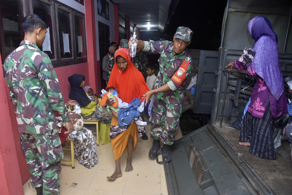 Indonesian soldiers help ethnic Rohingya women and children to step out of a military truck upon arrival at a temporary shelter after their boat landed in Pidie, Aceh province, Indonesia, Monday, Dec. 26, 2022. A second group in two days of weak and exhausted Rohingya Muslims landed on a beach in Indonesia's northernmost province of Aceh on Monday after weeks at sea, officials said. (AP Photo/Rahmat Mirza)