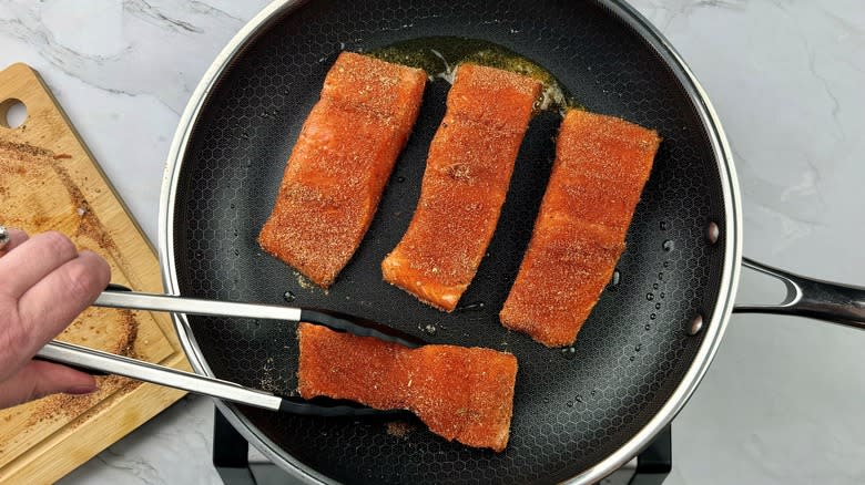hand moving salmon with tongs
