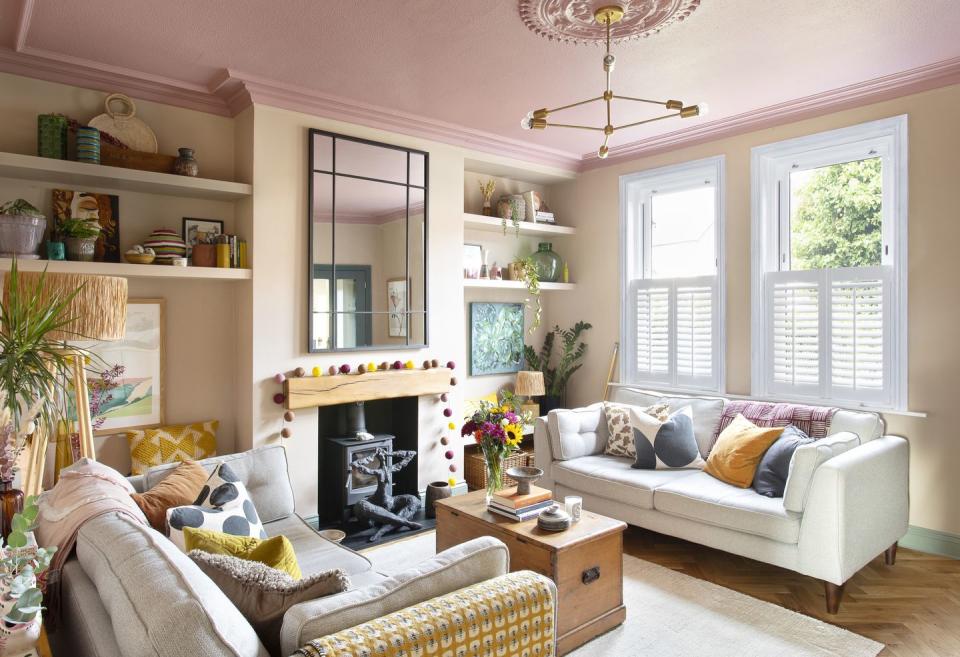 a pale pink living room with wooden blanket box and off white sofa