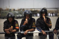 FILE - In this May 2, 2012 file photo, Egyptian riot police eat ice cream while securing the courthouse where ex-President Hosni Mubarak received a verdict in his trial for charges related to the death of protesters in Cairo, Egypt. The 2011 uprising led to the quick ouster of autocrat Hosni Mubarak. A decade later, thousands are estimated to have fled abroad to escape a state, headed by President Abdel Fattah el-Sissi, that is even more oppressive. (AP Photo/Manu Brabo, File)