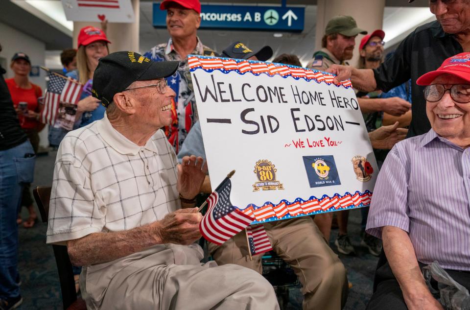 Sydney Edson, 100, of Lake Worth Beach, laughs as he is greeted by fellow veterans Saturday at Palm Beach International Airport.