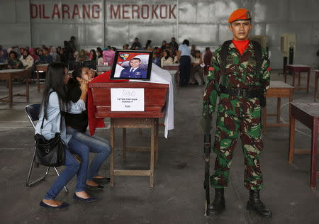 A woman cries beside the coffin of her husband, who is a victim of an Indonesian military C-130B Hercules aircraft that crashed into a residential area, at a military airbase in Medan, Indonesia July 1, 2015. REUTERS/Beawiharta