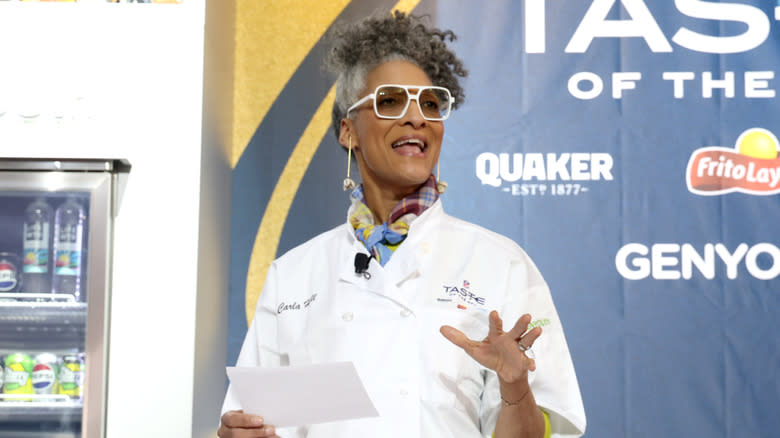 Kooky Carla Hall in an apron with her quirky white glasses