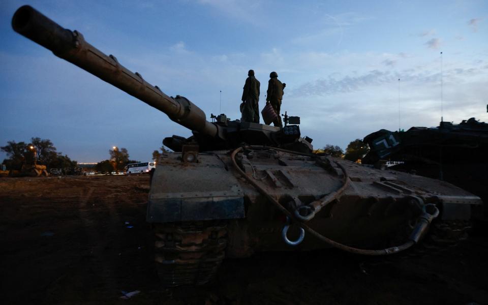 Israeli soldiers stand on an Israeli tank near the Israel-Gaza border