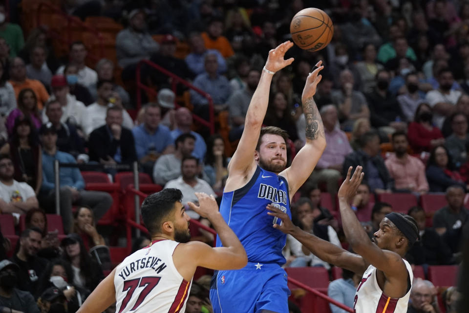 Dallas Mavericks guard Luka Doncic, center, passes past Miami Heat center Omer Yurtseven, left, and forward Jimmy Butler during the first half of an NBA basketball game, Tuesday, Feb. 15, 2022, in Miami. (AP Photo/Wilfredo Lee)