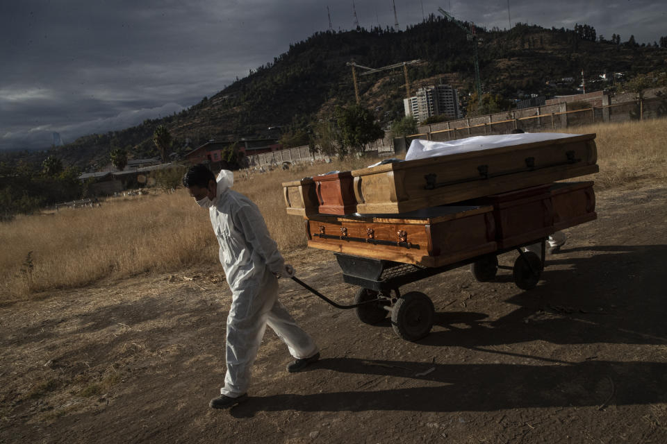 A funeral worker removes empty coffins that held remains that were later cremated, at La Recoleta cemetery in Santiago, Chile, Wednesday, April 21, 2021, amid the new coronavirus pandemic. (AP Photo/Esteban Felix)