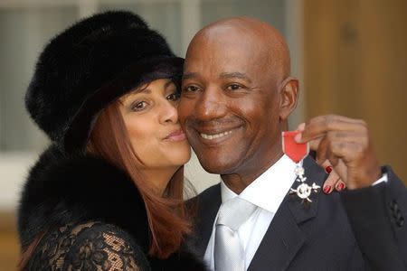 Errol Brown of British band Hot Chocolate holds his MBE (Member of the Order of the British Empire) with his wife Ginette after receiving the award for his services to pop music, from Britain's Queen Elizabeth II at Buckingham Palace, November 27, 2003. REUTERS/POOL/Fiona Hanson/Files
