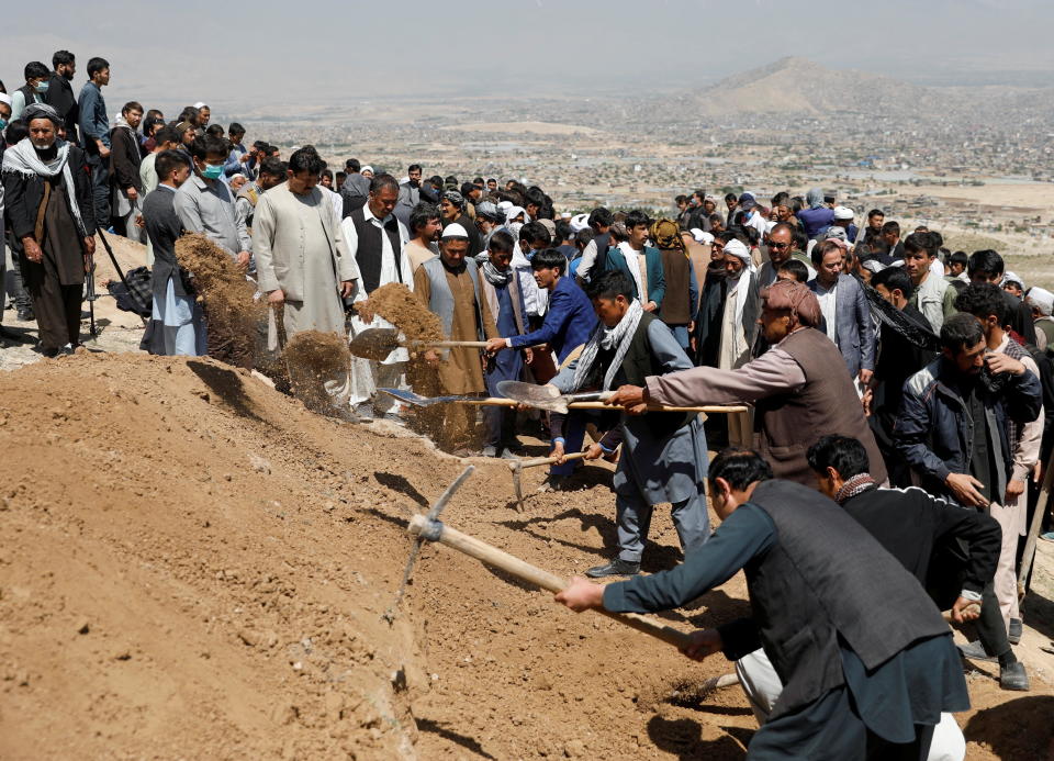 Men dig graves for the victims of Saturday's explosion at a girls' school, during a mass funeral ceremony in Kabul, Afghanistan on May 9, 2021. / Credit: STRINGER / REUTERS