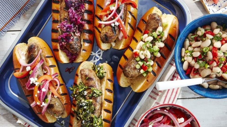 grilled sausages on grilled hot dog buns with a variety of toppings