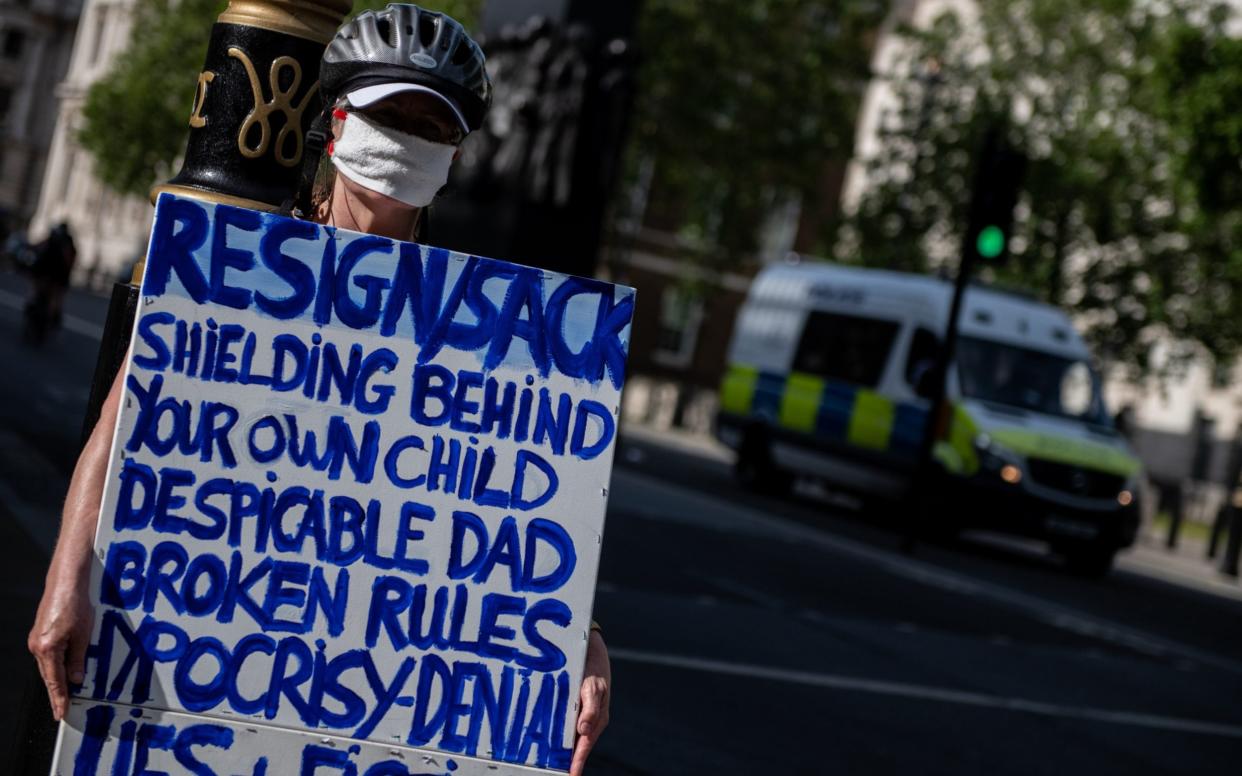 A lone protester wears a face mask and holds a placard calling on Dominic Cummings - Getty Images