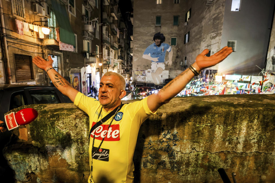 Un hombre con la casaca del Napoli hace declaraciones frente a un mural dedicado a Diego Maradona en Nápoles poco después de la noticia de la muerte del astro argentino el 25 de noviembre del 2020. (Alessandro Garofalo/LaPresse via AP)