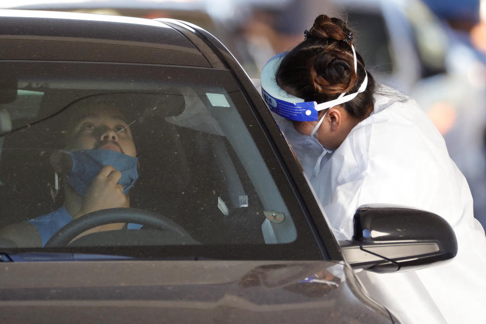 A person is tested for the COVID-19 Coronavirus Tuesday, July 28, 2020 at Cesar Chavez City Park in Phoenix. The two-week testing event is aimed at bringing tests to Phoenix's Laveen neighborhood, home to many Latinos and Blacks who have been disproportionately affected by the coronavirus. Latino leaders say governments need to do more to communicate effectively with Hispanic communities to ensure people know where to get tested and encourage them to participate. (AP Photo/Matt York)