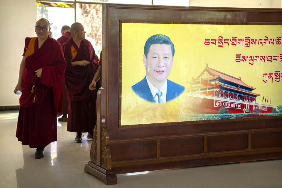 Varios monjes pasan junto a un retrato del presidente chino Xi Jinping y la plaza Tiananmén de Beijing en el Colegio Budista Tibetano el 31 de mayo del 2021. (AP Photo/Mark Schiefelbein)