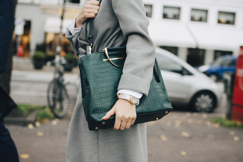 Woman holding green shoulder bag while walking outdoors. (Getty Images/Maskot)