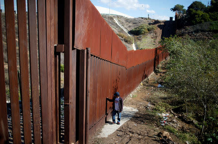 FILE PHOTO: A migrant, part of a caravan of thousands from Central America trying to reach the United States, crosses a flooded area next to the border wall as he tries to cross from Mexico to the U.S., in Tijuana, Mexico, December 7, 2018. REUTERS/Mohammed Salem