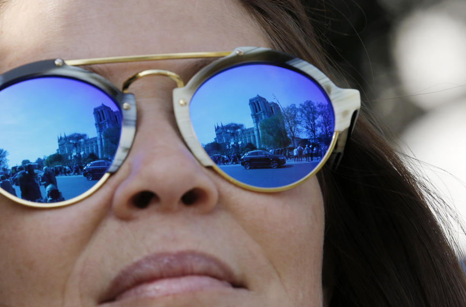 The Notre Dame Cathedral is reflected in the sunglasses of an onlooker in Paris, Thursday, April 18, 2019. Nearly $1 billion has already poured in from ordinary worshippers and high-powered magnates around the world to restore Notre Dame Cathedral in Paris after a massive fire. (AP Photo/Christophe Ena)