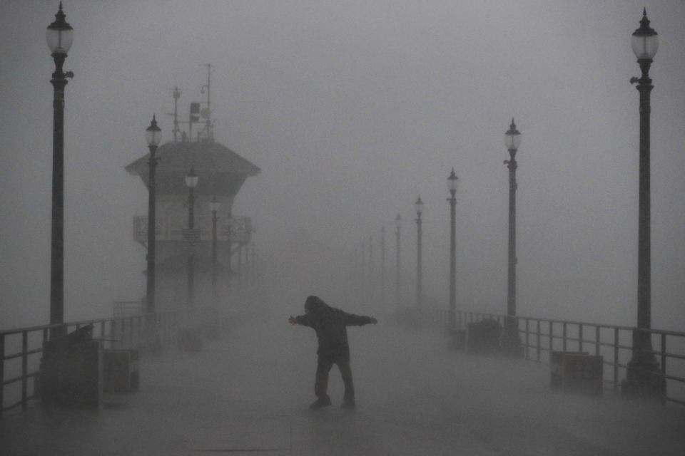 Un hombre lucha con las ráfagas de viento y la fuerte lluvia mientras camina por el muelle, el viernes 17 de febrero de 2017, en Huntington Beach, California. (AP Foto/Jae C. Hong)