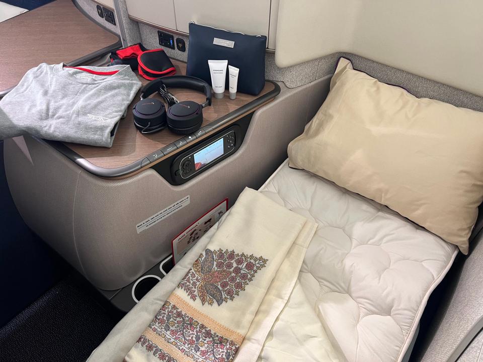 The bed in lie-flat mode with amenity kit and pajamas next to it.
