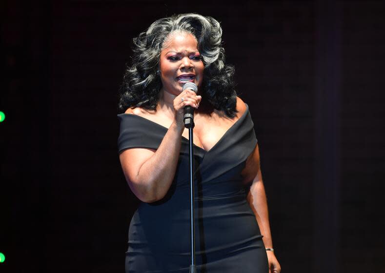 Comedian Mo'Nique, in black, off-the-shoulder dress, performs onstage