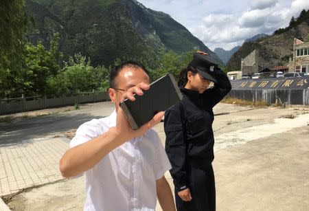 A local official and a police offcer prevent journalists from advancing toward the site of a landslide near the village of Xinmo, Mao County, Sichuan Province, China June 25, 2017. Picture taken June 25, 2017. REUTERS/Sue-Lin Wong