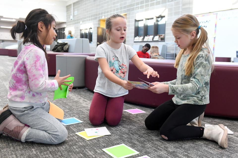 First graders Marlee Hendricks, Bailey Vongkhamchanh and Vayda Peterreins discuss strategy for placing colored tiles as an early form of coding education on Thursday, December 8, 2022, at Adventure Elementary in Harrisburg.